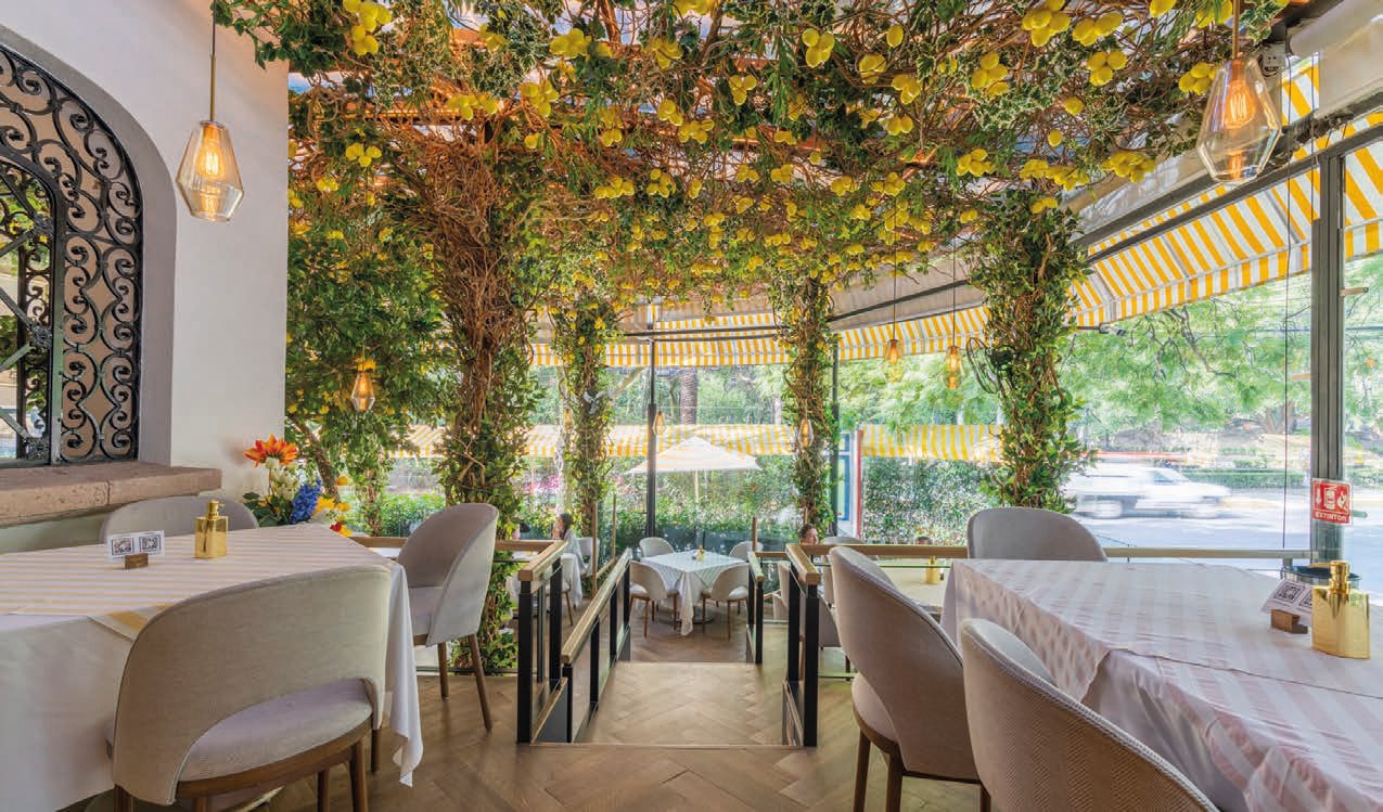 El interior luminoso de Mandolina con mesas, vegetación y limones