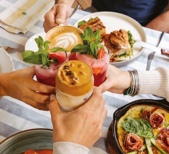 Amigos brindan con bebidas frescas alrededor de una mesa de brunch